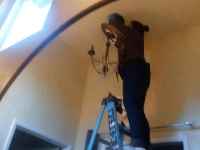 Electrician installing a chandelier in a Red Rock residence